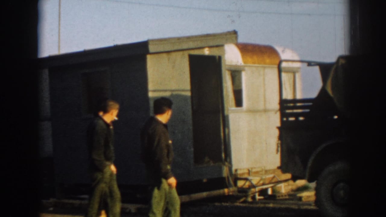 Men in military-style clothing walk past a portable trailer and dark truck in the Ephesus, Turkey home-movie scene.