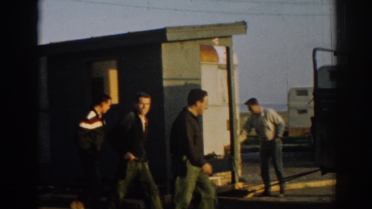 Several men in work or military-style clothing move around an open portable structure in 1962 Ephesus, Turkey footage.