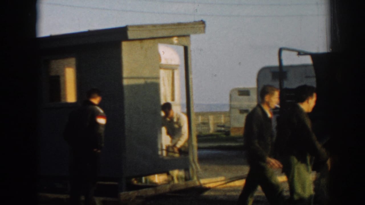 Men in military-style uniforms cross the frame near a small portable structure and parked truck in the 1962 Turkey clip.