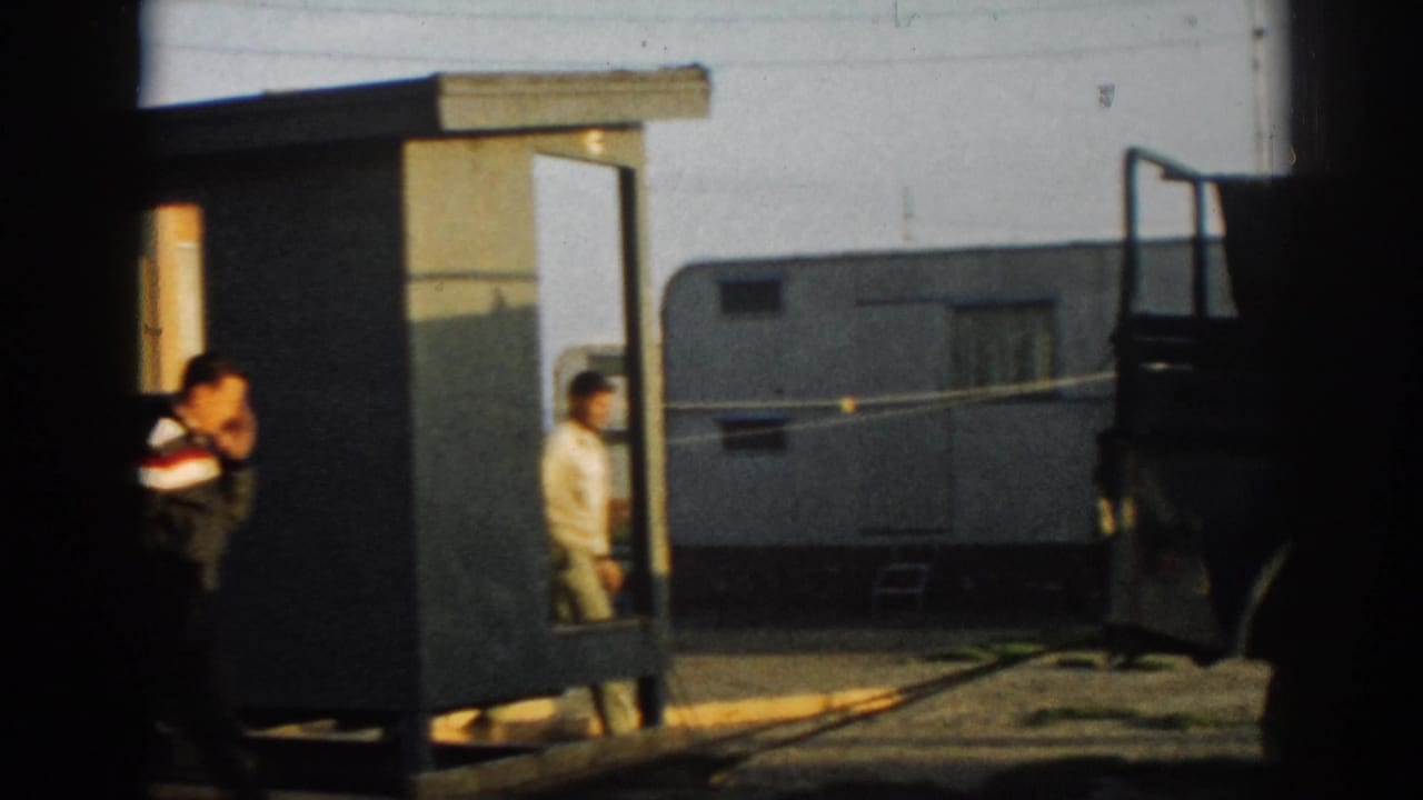 Men stand beside a small shelter at the Ephesus camp, with a trailer and military vehicle nearby.