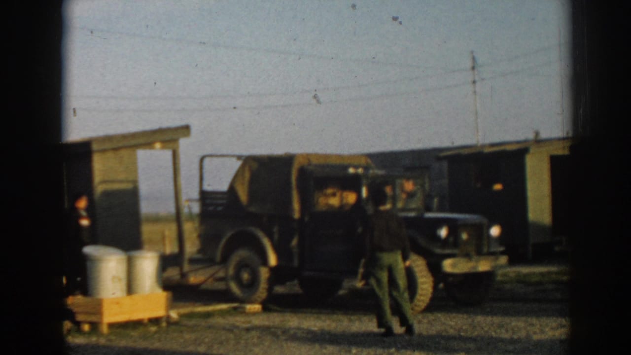 A canvas-covered military truck is parked beside a small shelter in the 1962 Ephesus camp scene.
