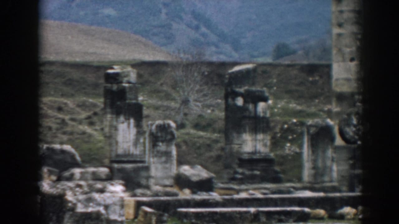 Ephesus archaeological ruins in 1962, showing upright stone columns, low remains, and muted hills in soft 8mm color.