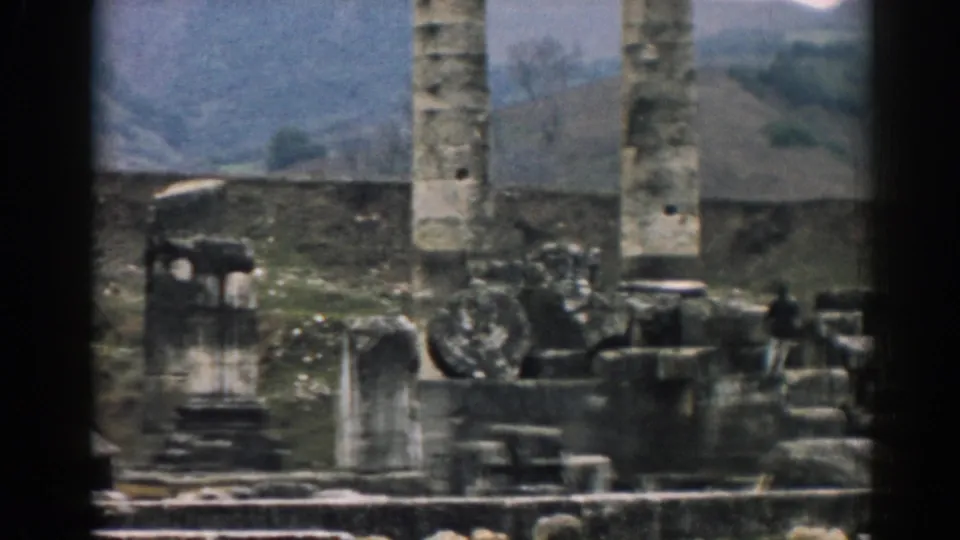 1962 8mm view of Ephesus ruins with tall stone columns, broken masonry, and rolling hills beyond the site.