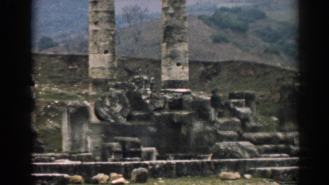 1962 home-movie frame showing Ephesus stone columns, low walls, rubble, and distant hills in soft focus.