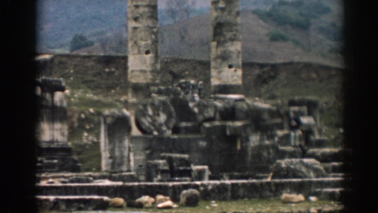1962 Ephesus frame with colossal weathered columns, scattered stone fragments, and a hilly background.