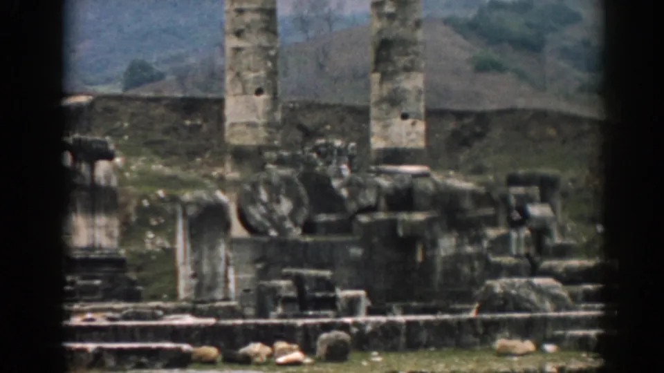 1962 Ephesus frame with colossal weathered columns, scattered stone fragments, and a hilly background.