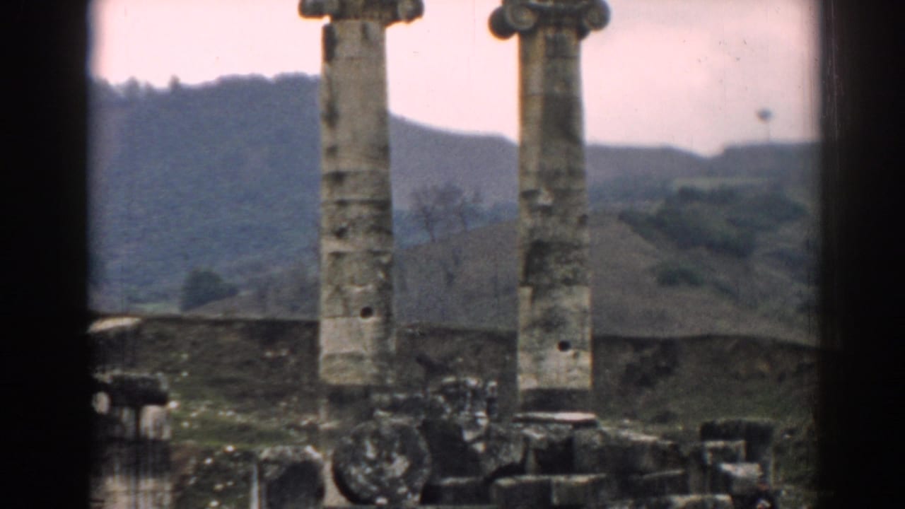 1962 Ephesus frame showing paired stone columns, broken architectural pieces, and the surrounding hillside.