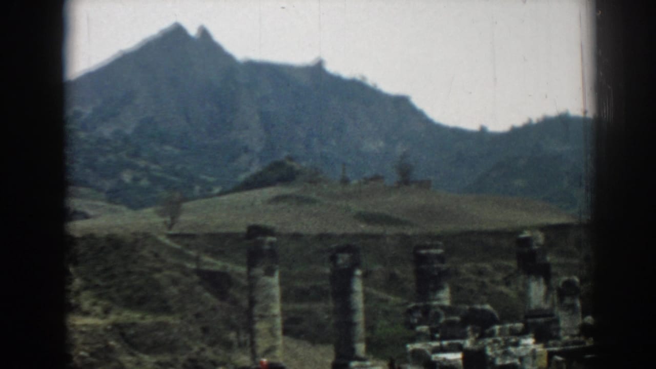 Ephesus travel footage from 1962 frames stone columns and low ruins against hills and a dark mountain ridge.