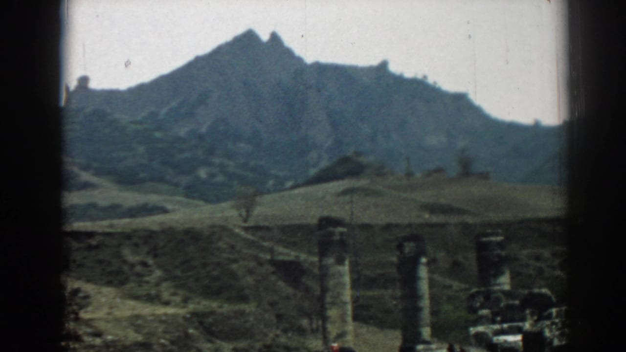The 8mm frame shows Ephesus ruins low in the foreground, with rolling terrain and a rugged mountain forming the backdrop.