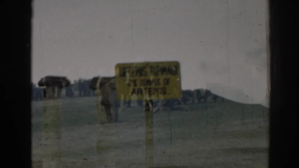 1962 Ephesus travel frame showing a yellow Temple of Artemis sign near parked vehicles under an overcast sky.