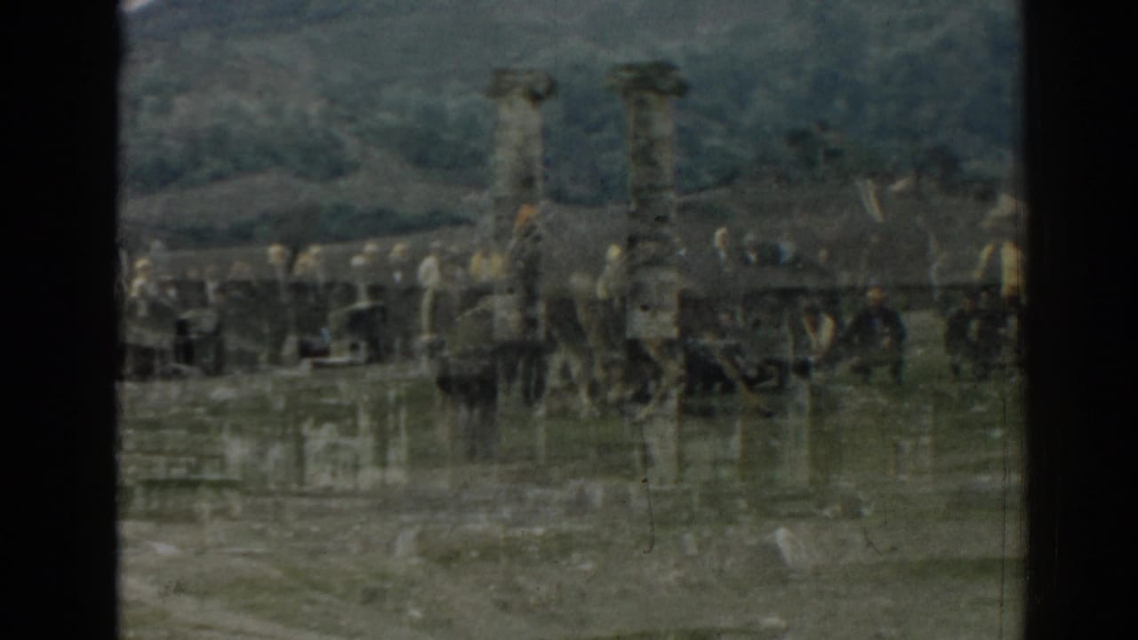 Tourists appear near columns, horses or carts, and parked vehicles at the Ephesus ruins in a soft 8mm frame.
