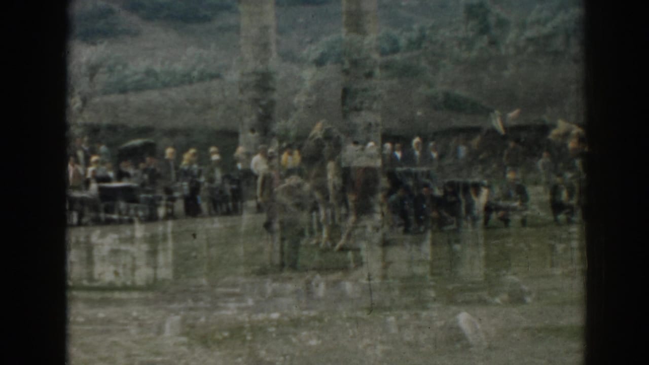 A 1962 Ephesus home-movie view of tourists clustered near a standing column and scattered ruins.