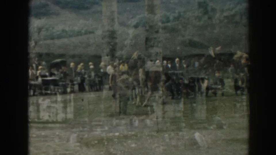 A 1962 Ephesus home-movie view of tourists clustered near a standing column and scattered ruins.