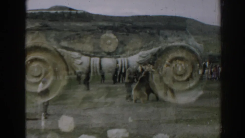 Near the end of the 1962 Ephesus clip, the bear and men pause or turn by spiral stonework as visitors stand farther back.