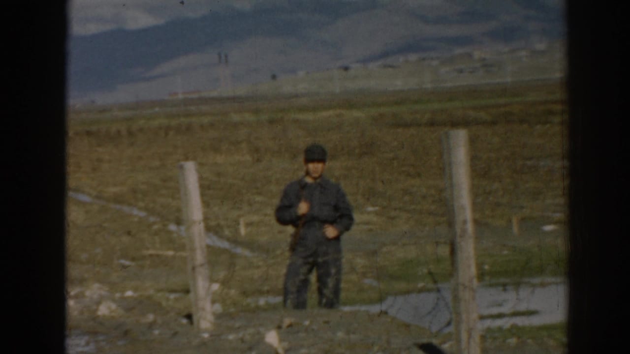 In 1962 Ephesus, Turkey footage, a man stands near fence posts in an arid field with hills behind him.