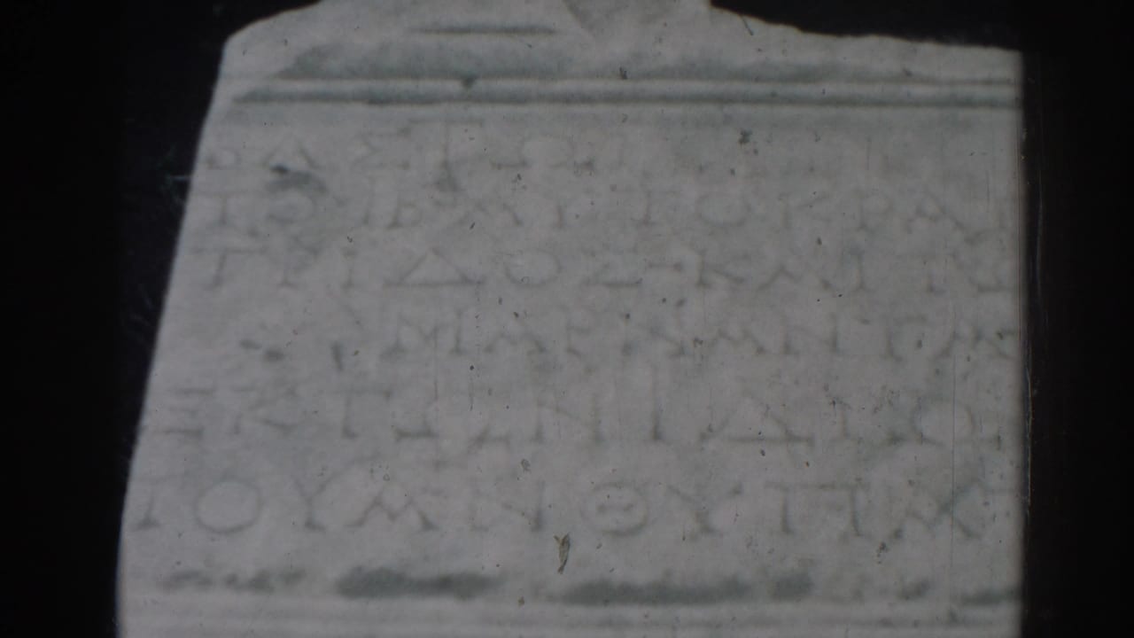 Close view of a weathered inscribed stone block with dark 8mm frame edges.