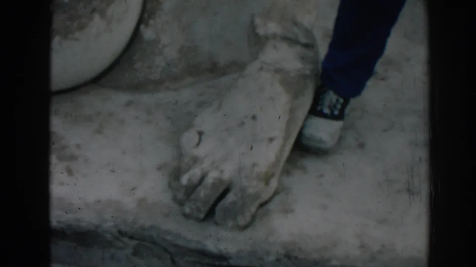 Home-movie view at Ephesus with a tourist's modern shoe placed near a massive ancient carved foot.