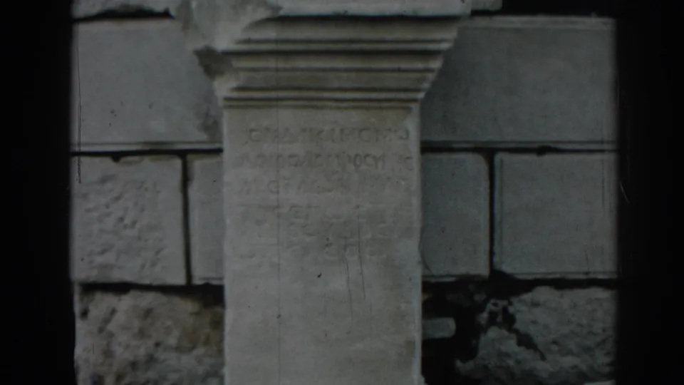 1962 8mm view at Ephesus showing a weathered stone inscription panel or column framed by surrounding masonry.