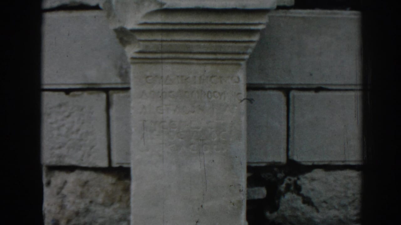 Visitor-shot 8mm frame at Ephesus focusing on a pale stone inscription set against darker surrounding blocks.