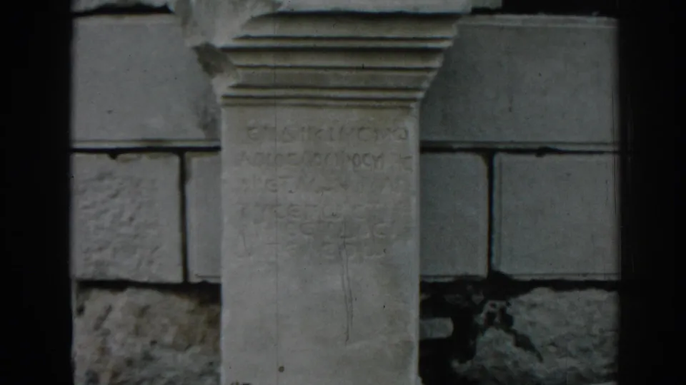 1962 Ephesus home-movie frame showing the inscription stone more fully, with block masonry and film wear visible.