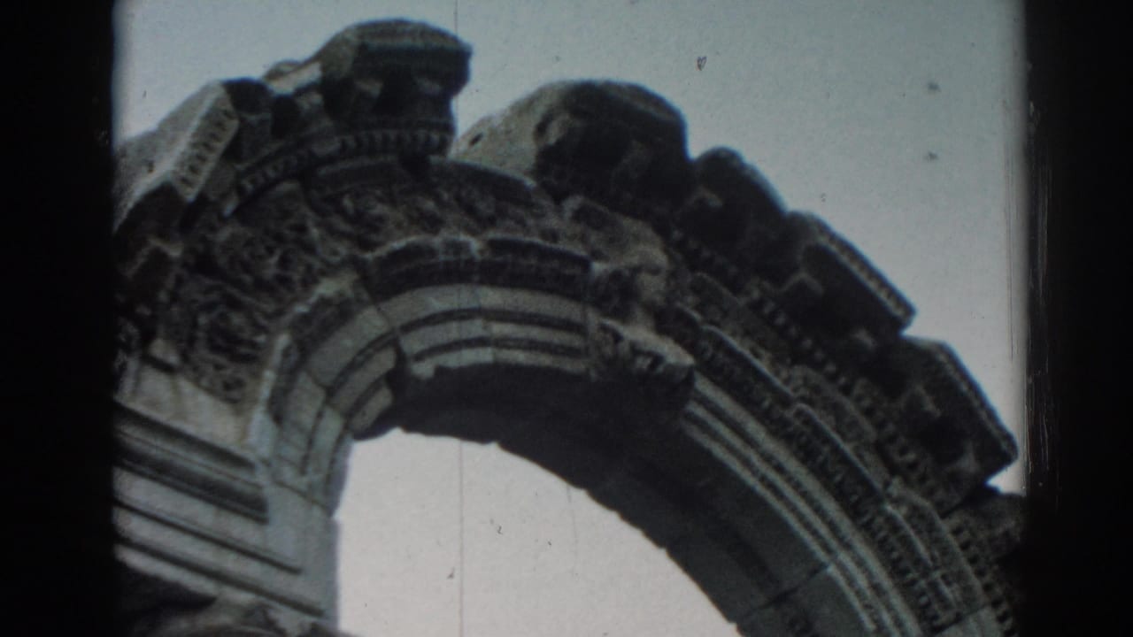 Close view of a weathered carved stone arch against pale sky.