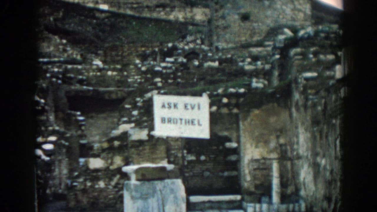 Final 1962 Ephesus frame showing the posted sign, eroded wall surfaces, and dark 8mm frame edges.