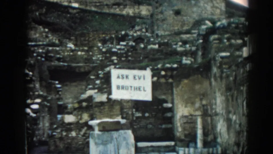 Final 1962 Ephesus frame showing the posted sign, eroded wall surfaces, and dark 8mm frame edges.