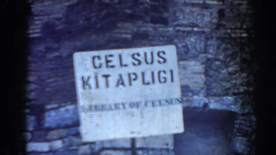 1962 Ephesus frame showing a Library of Celsus sign before weathered masonry and a dark arched opening.