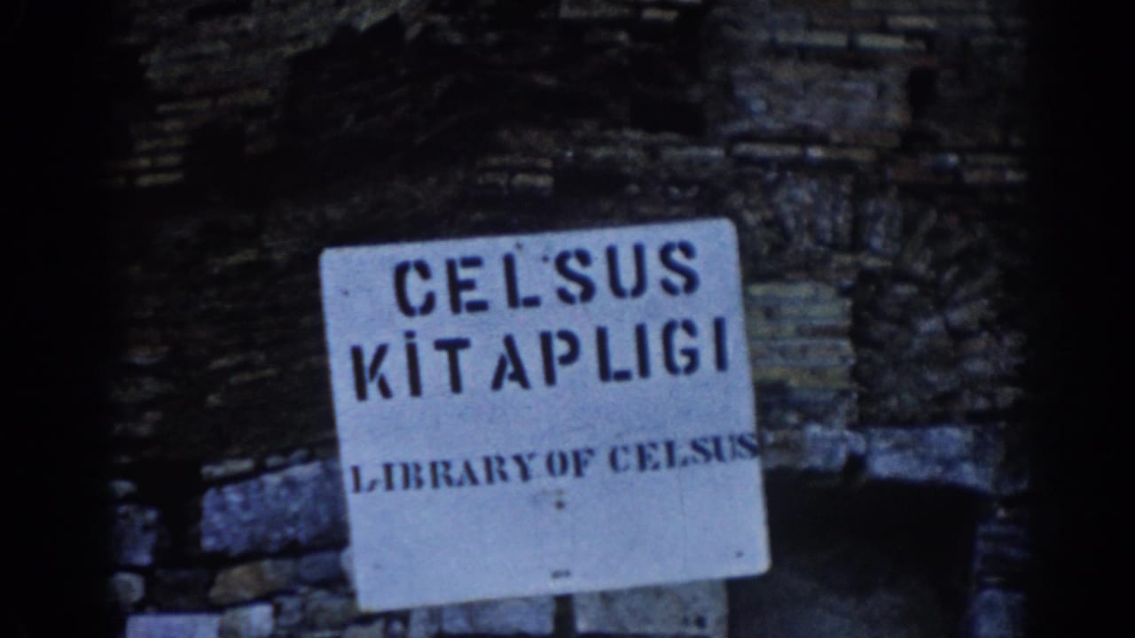 1962 Ephesus home-movie frame focused on a Library of Celsus sign near ancient stonework and a shadowed arch.