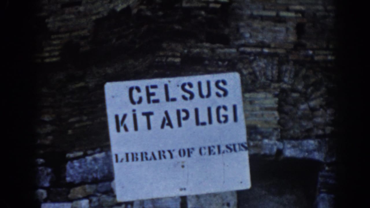 White Library of Celsus sign mounted against dark ancient stone ruins.