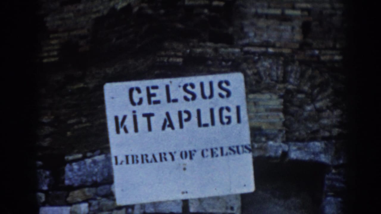 1962 Ephesus travel-film view of the Library of Celsus sign beside rough ancient masonry and shadowed ruins.