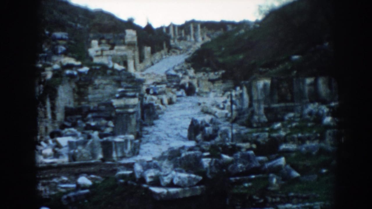 1962 Ephesus frame with the camera closer to the stone path, rubble, column pieces, and ruin walls.