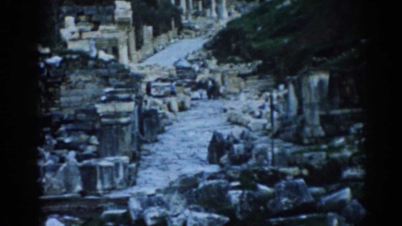 1962 8mm view of a stone path through the ruins at Ephesus, with broken masonry, walls, and a distant visitor-like figure.