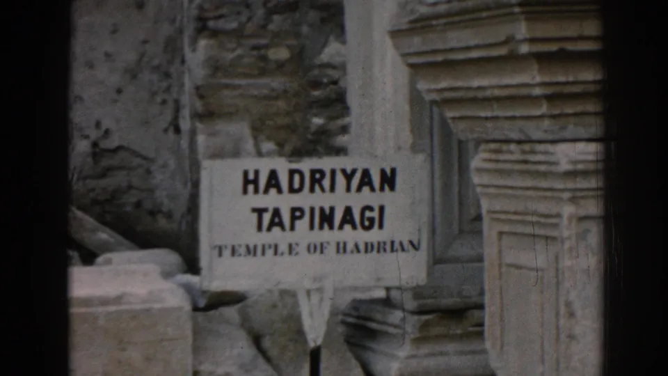1962 8mm frame at Ephesus showing a Hadriyan Tapinagi Temple of Hadrian sign set between worn stone remains.