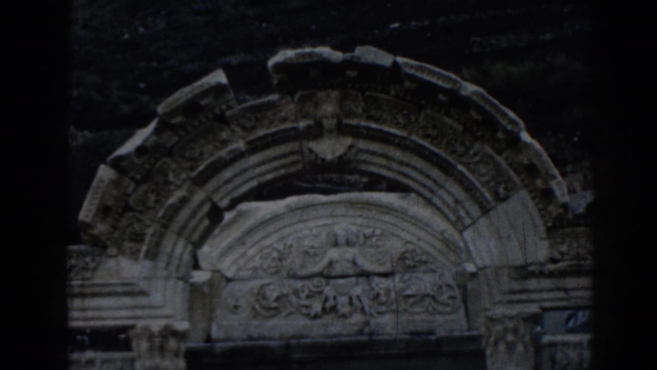 1962 8mm frame of the Temple of Hadrian at Ephesus, focusing on an arched stone surround with relief carving.