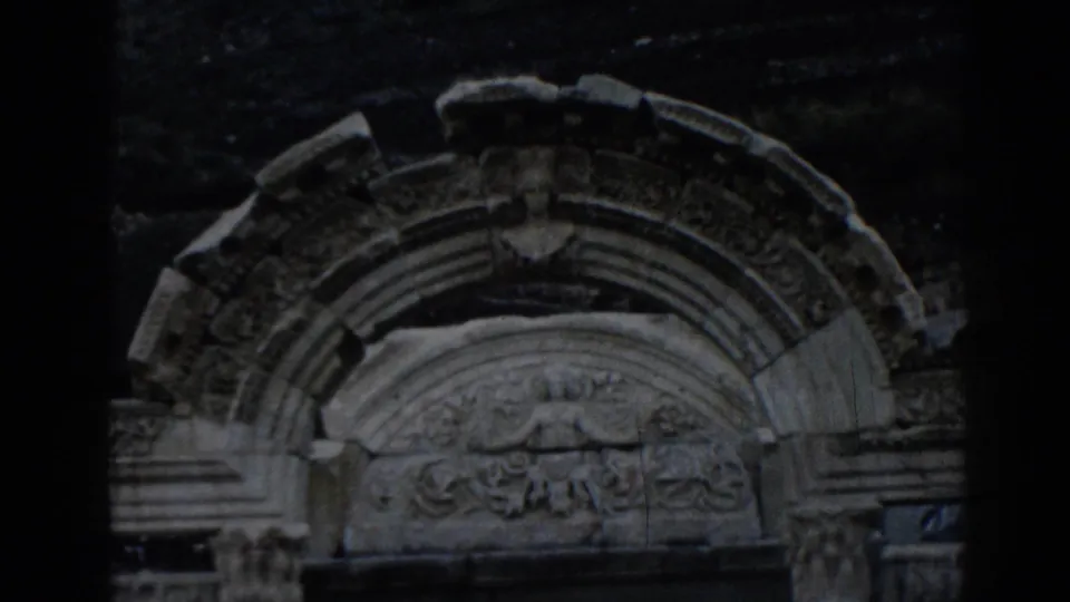1962 8mm frame of the Temple of Hadrian at Ephesus, focusing on an arched stone surround with relief carving.