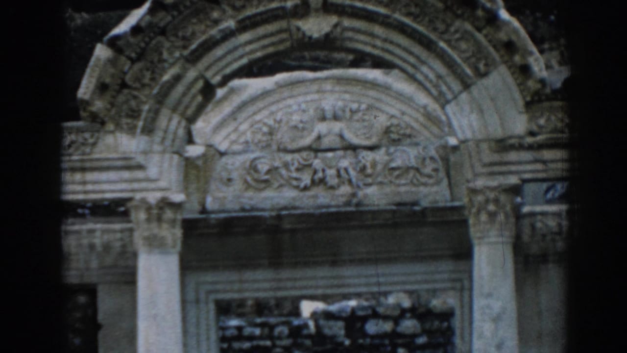 1962 Ephesus frame showing the Temple of Hadrian arch, decorative relief, vertical supports, and a partially ruined doorway.