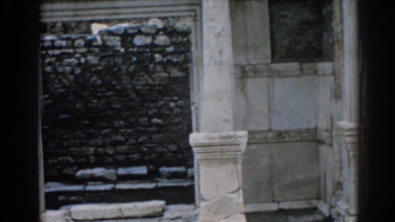 1962 Ephesus frame holding on pale architectural columns and a dark stone wall within the ancient ruin.