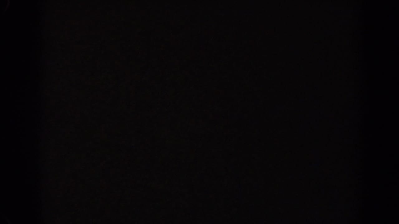 Underexposed 8mm frame from the Ephesus clip, with the scene largely obscured by darkness and film border.
