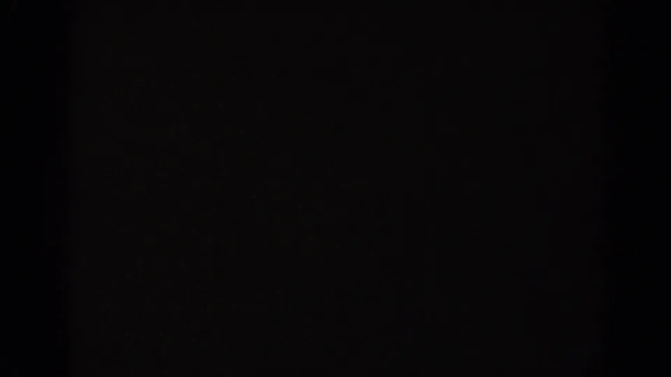 Underexposed 8mm frame from the Ephesus clip, with the scene largely obscured by darkness and film border.