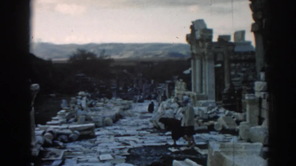 Ephesus, Turkey, in 1962, with visitors walking through a ruin-lined path under a pale sky.