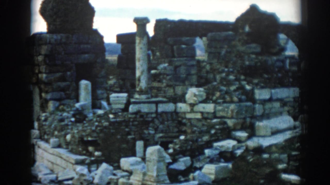 1962 Ephesus ruins frame showing weathered columns, stacked masonry, scattered stones, vegetation, and handheld 8mm framing.