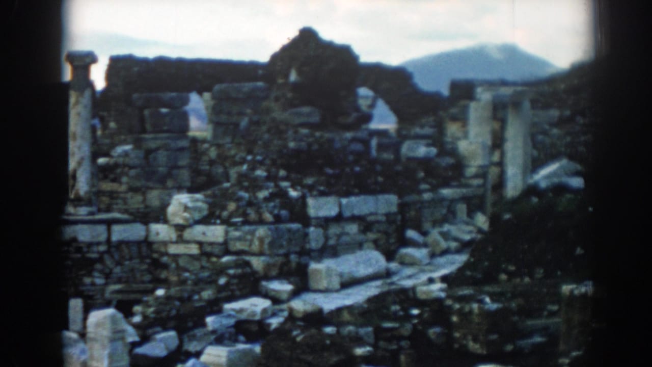 Late frame from 1962 Ephesus 8mm footage showing weathered stone ruins, scattered blocks, columns, and distant hills.