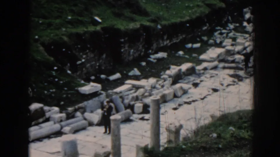 1962 Ephesus home-movie view of a visitor among upright columns, broken masonry, and a sunlit stone walkway.