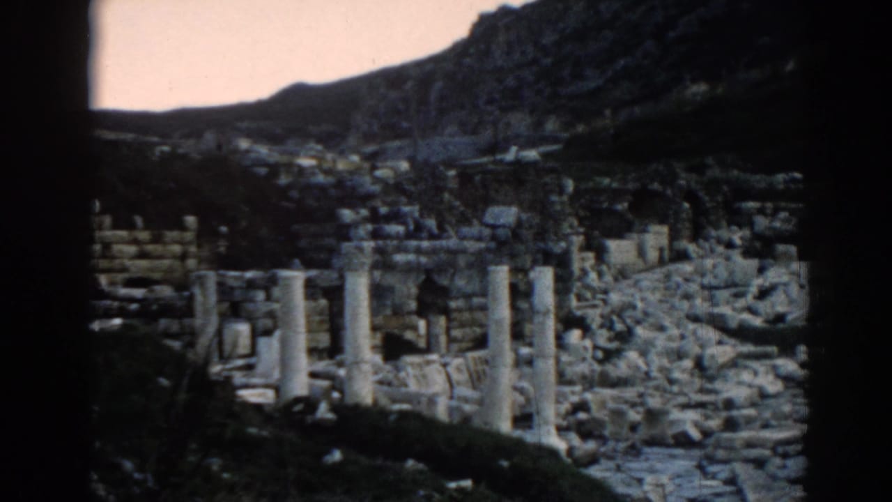 1962 8mm view of Ephesus ruins in Turkey, showing broken columns, stone debris, and a dark film border.