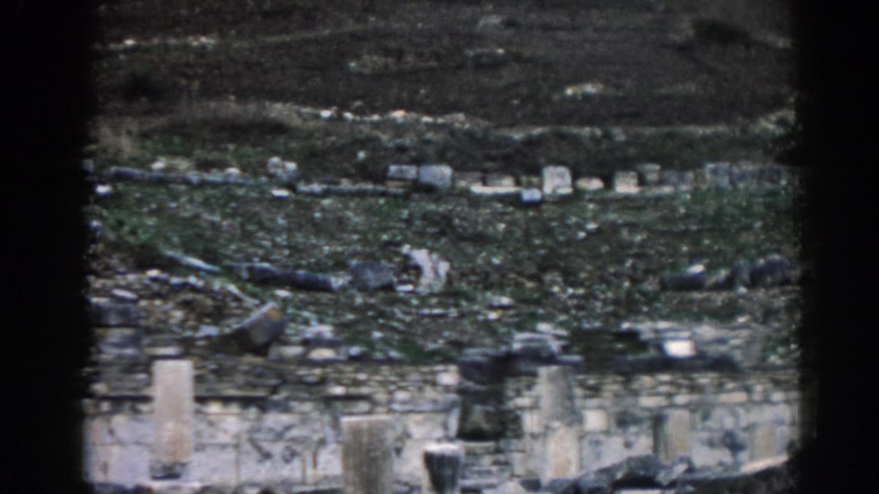 Weathered stonework and scattered pale rocks across a grassy hillside slope.