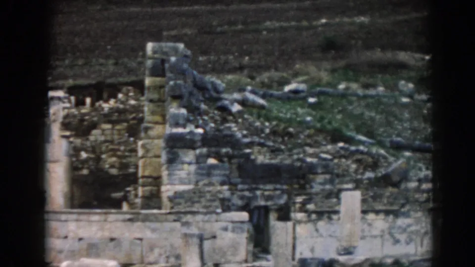 1962 Ephesus frame with ancient stonework, broken masonry, scattered rubble, and subdued cloudy-day color from an 8mm scan.