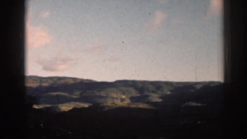 1962 8mm home-movie frame from Ephesus, Turkey, showing distant hills and soft clouds through dark frame edges.