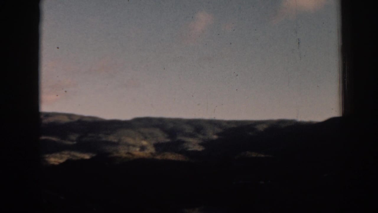 Distant hills and muted sky divided by dark vertical frame edges.