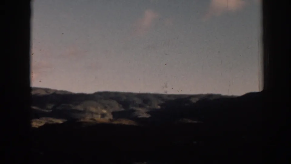 1962 8mm scenic frame from Ephesus, Turkey, with a shadowed foreground, rolling hillside, and lightly clouded sky.